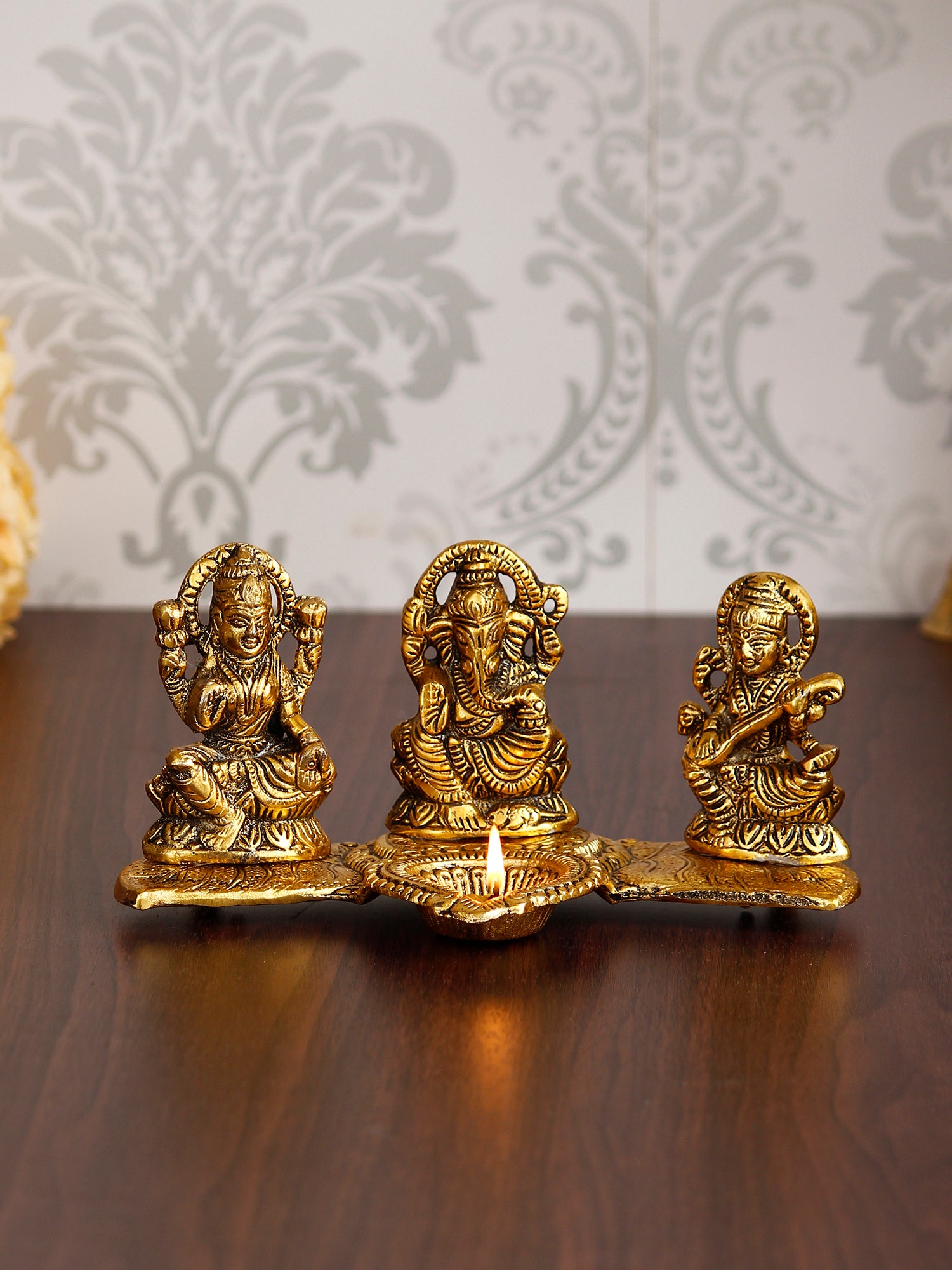 Gold Metal Handcrafted Laxmi Ganesha Saraswati Idols with Diya on Leaf Chowki