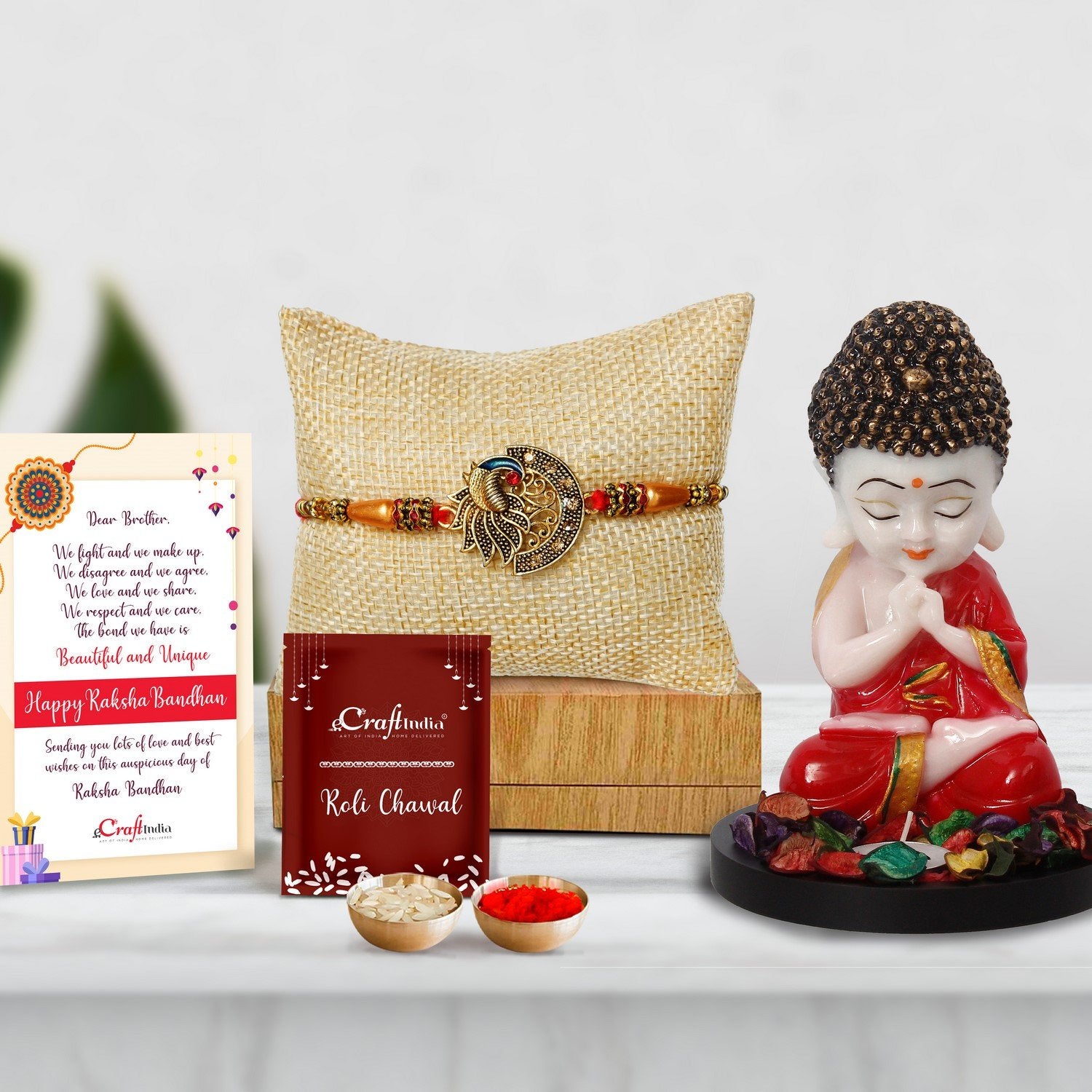 Designer Peacock Rakhi with Praying Red Monk Buddha with Wooden Base, Fragranced Petals and Tealight and Roli Chawal Pack, Best Wishes Greeting Card