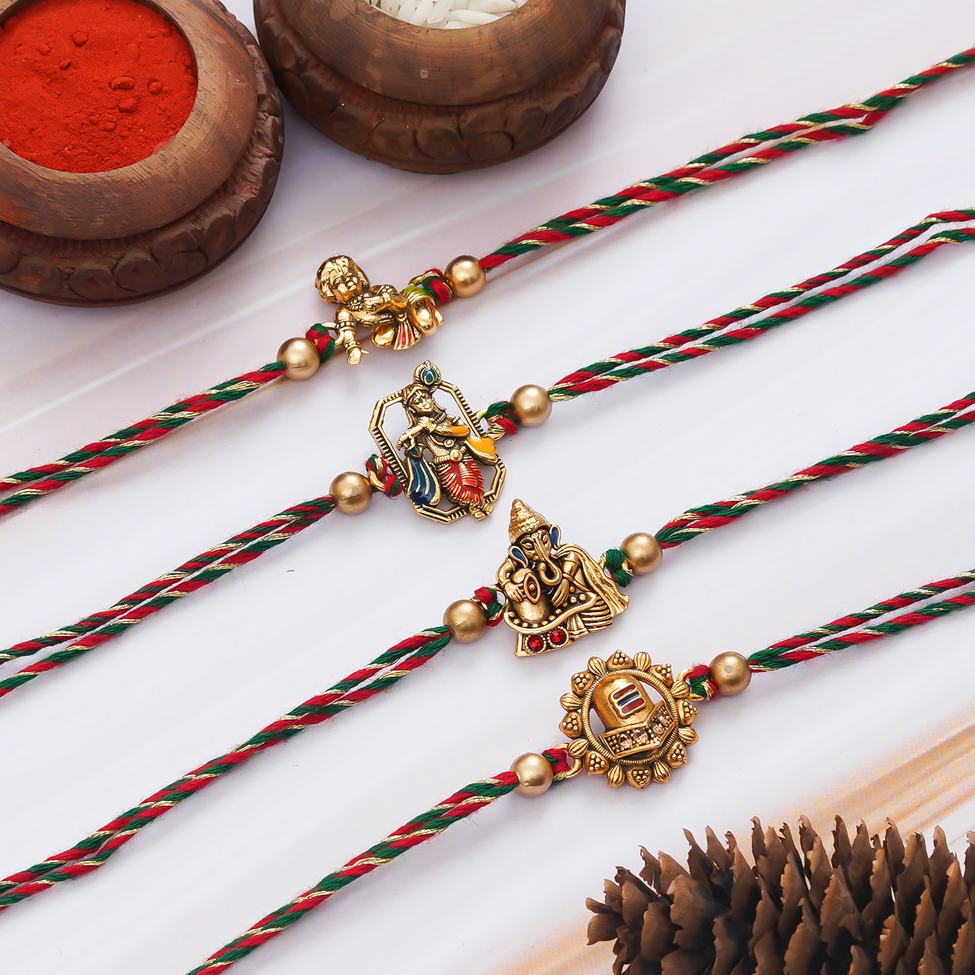 eCraftIndia Set of 4 Golden Laddu Gopal, Lord Krishna Playing Flute, Lord Ganesha, and Shivling Religious Rakhis with Green Red Threads, and Roli Chawal Pack