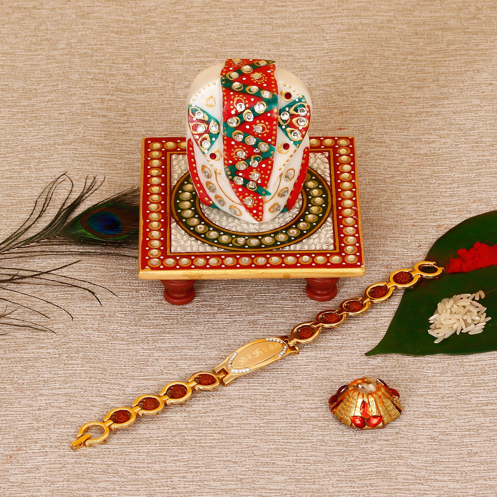 Designer Bracelet Religious Rakhi with Lord Ganesha on Kundan Studded Marble Chowki and Roli Tikka Matki