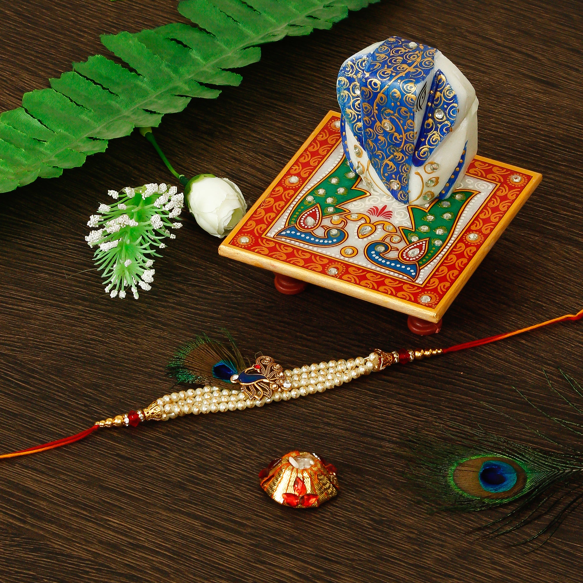 Designer Pearl Morpankh Rakhi with Lord Ganesha on Marble Chowki and Roli Tikka Matki