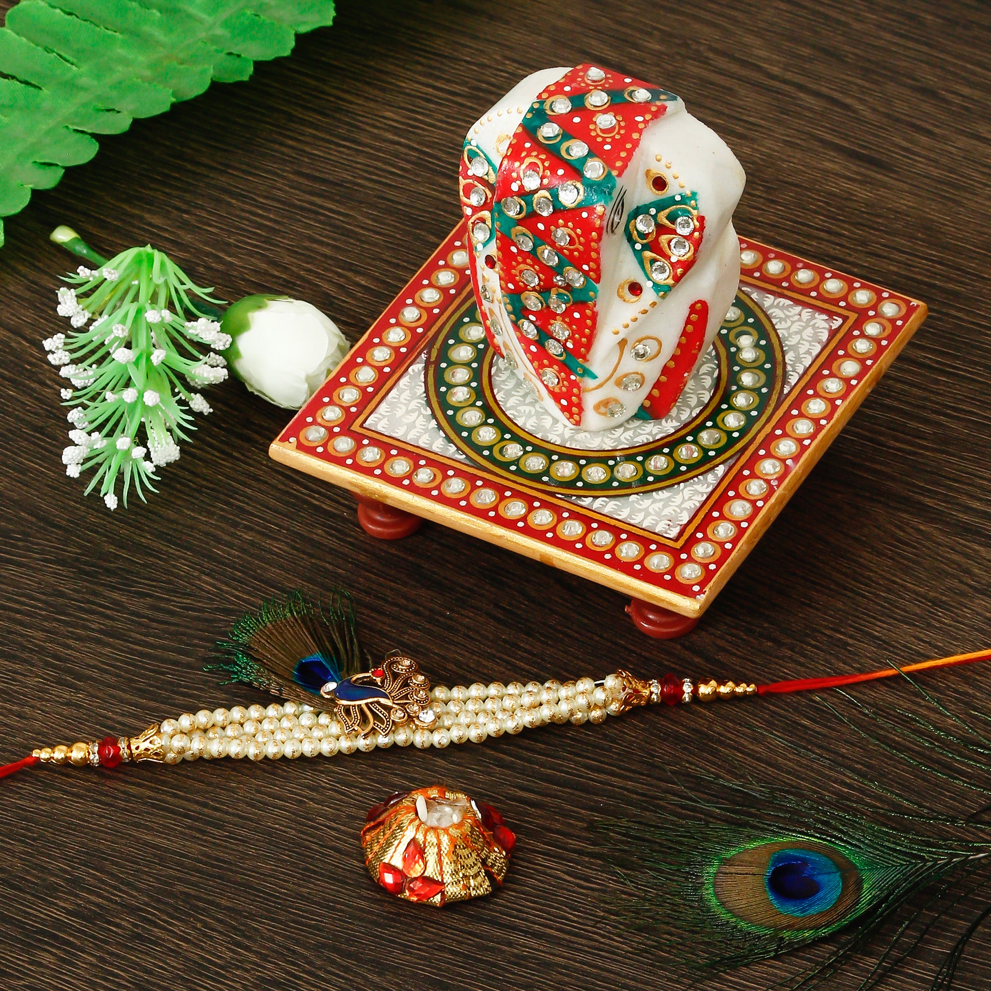 Designer Pearl Morpankh Rakhi with Lord Ganesha on Kundan Studded Marble Chowki and Roli Tikka Matki