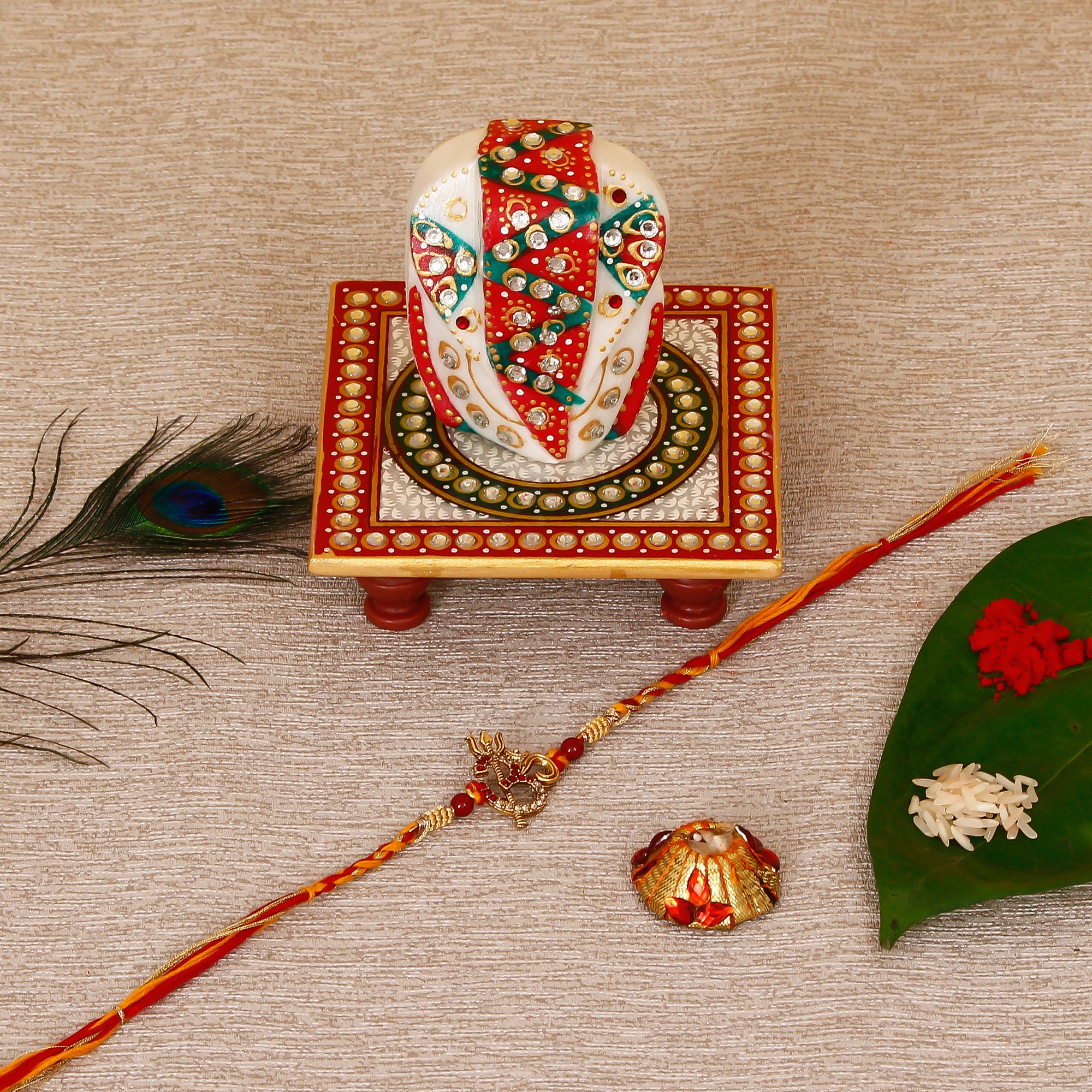 Designer Religious OM Rakhi with Lord Ganesha on Kundan Studded Marble Chowki and Roli Tikka Matki