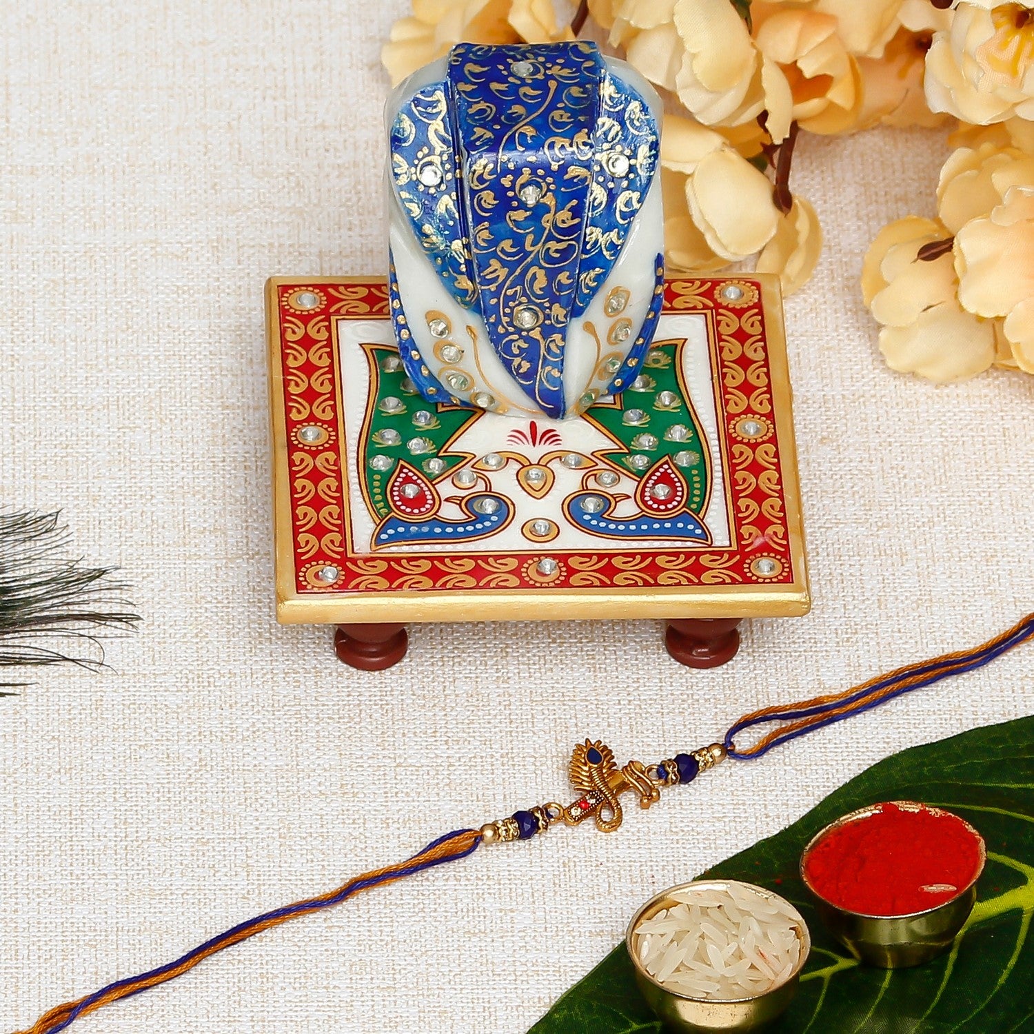 Designer Mor Pankh with Flute Rakhi with Lord Ganesha on Marble Chowki and Roli Chawal Pack