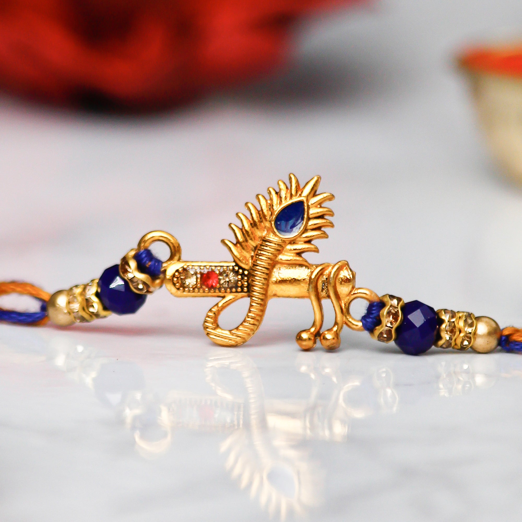 Designer Mor Pankh with Flute Rakhi with Lord Ganesha on Marble Chowki and Roli Chawal Pack 1