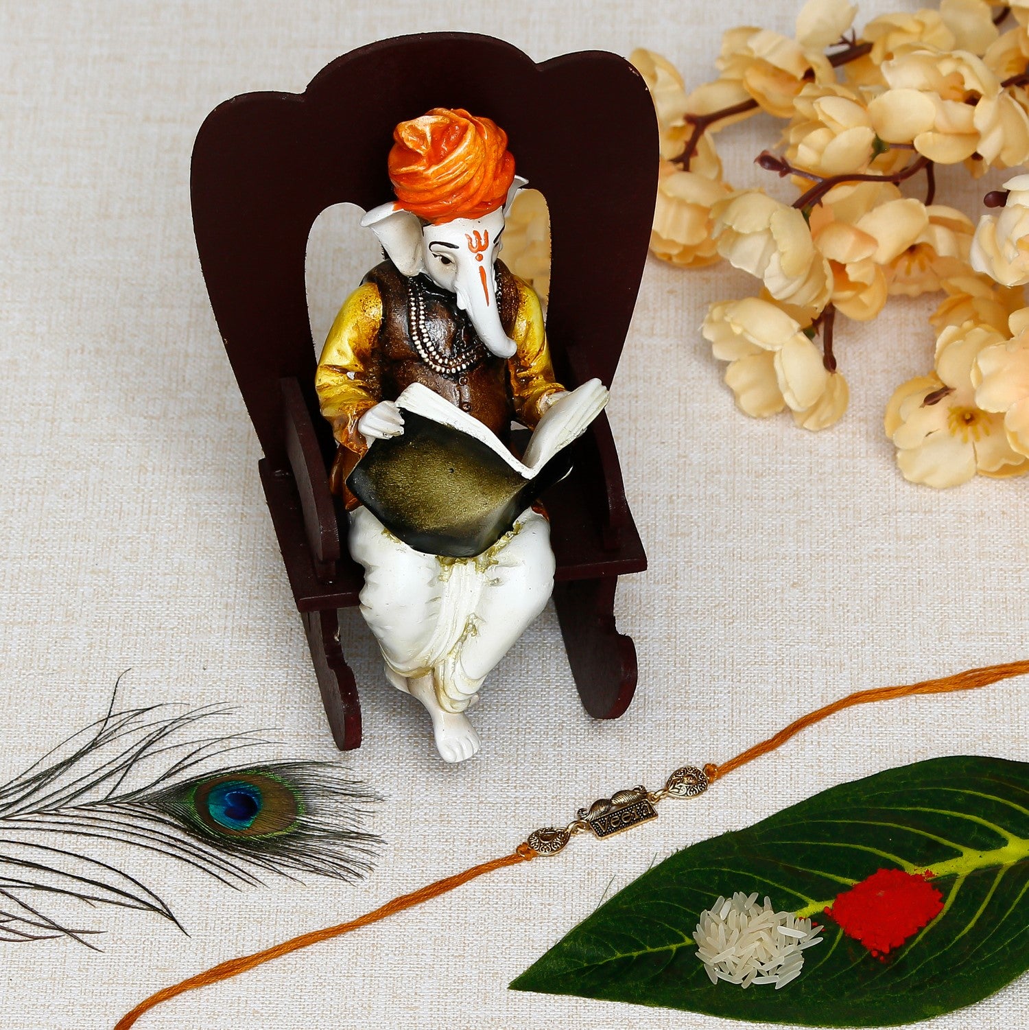 Designer Veera Rakhi with Lord Ganesha reading Book on Wooden Chair and Roli Chawal Pack
