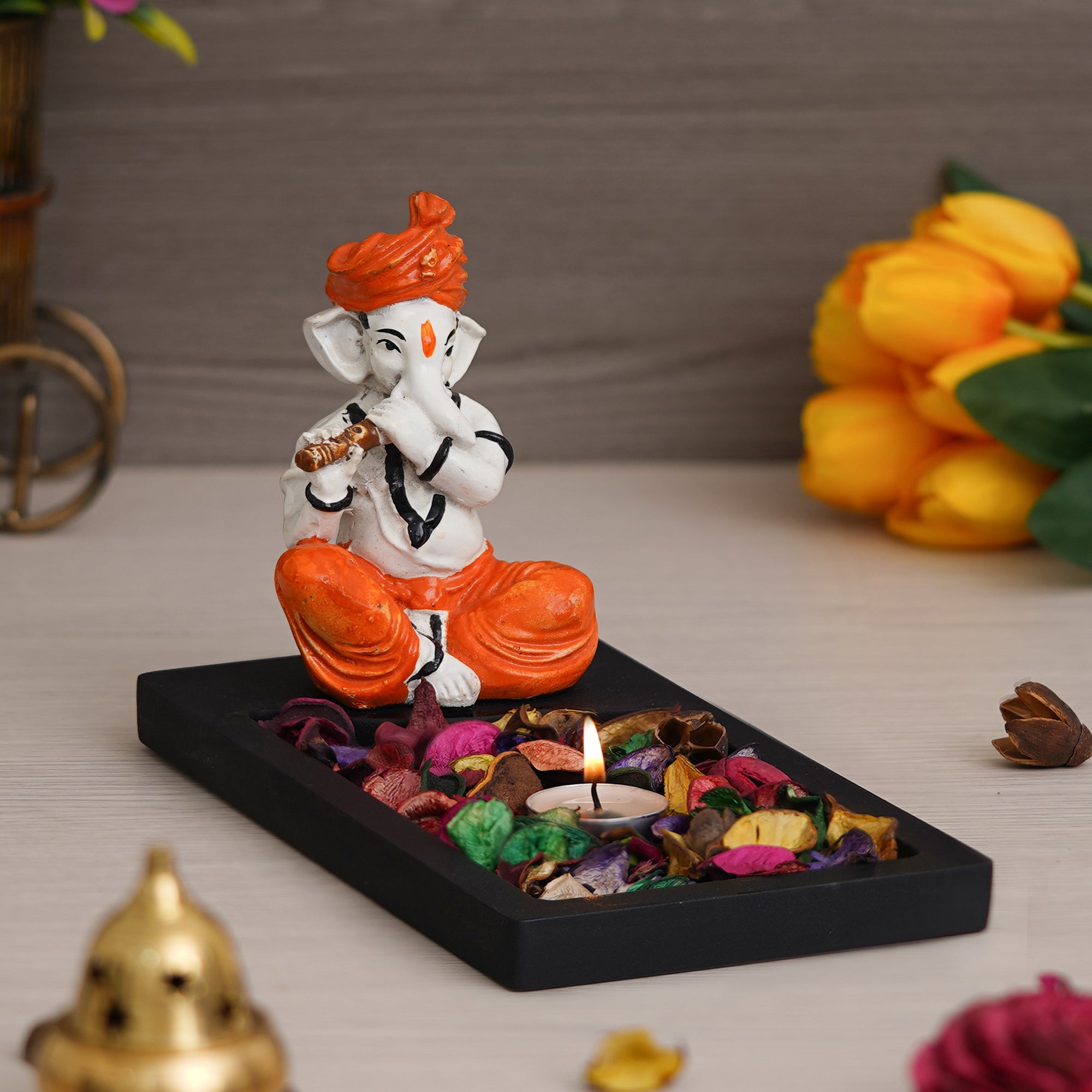 Orange, Brown, White & Black Polyresin Ganesha Playing Flute Showpiece with Rectangle Wooden Base Plate, Fragranced Petals & Tealight